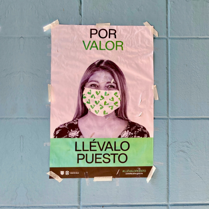 Cartel con fotografía de una mujer usando cubrebocas con la leyenda 'por valor llévalo puesto'